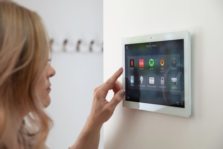 A woman using a Control4 interface mounted on a wall.